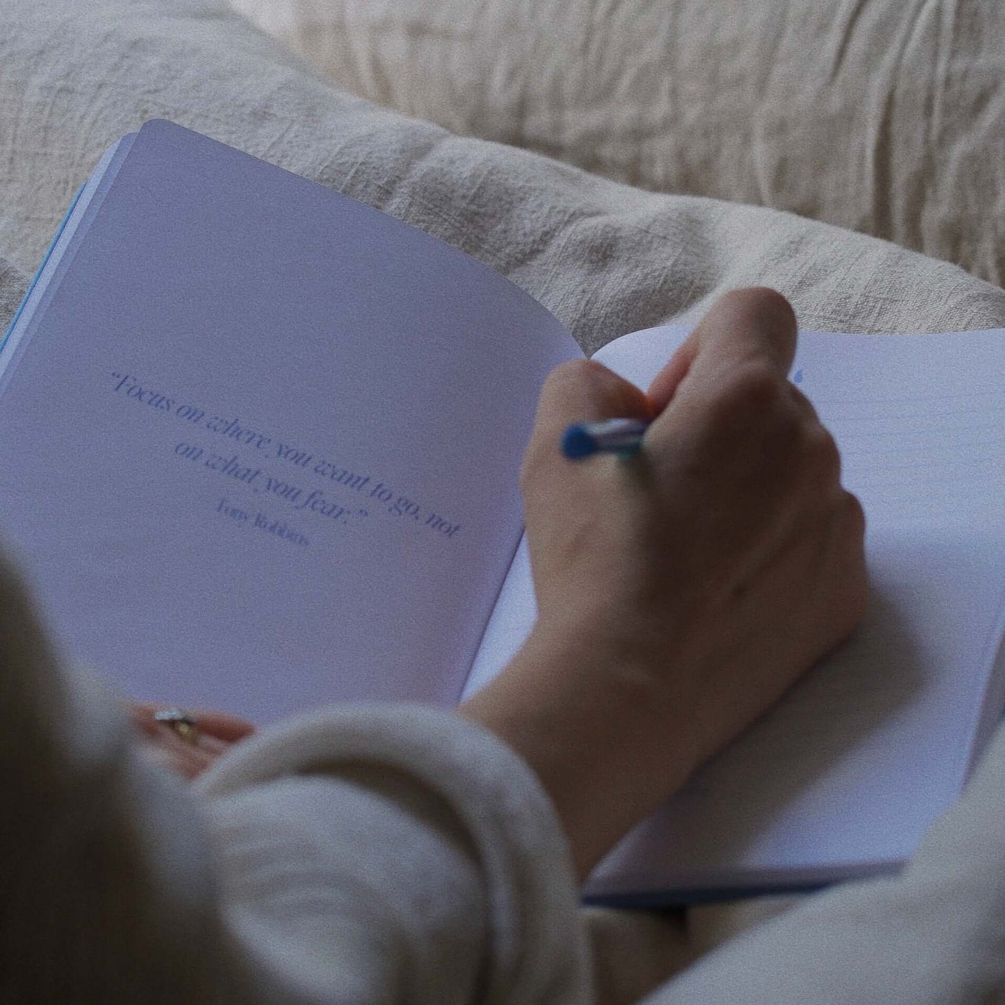 Girl writing in her journal on her bed in her morning routine